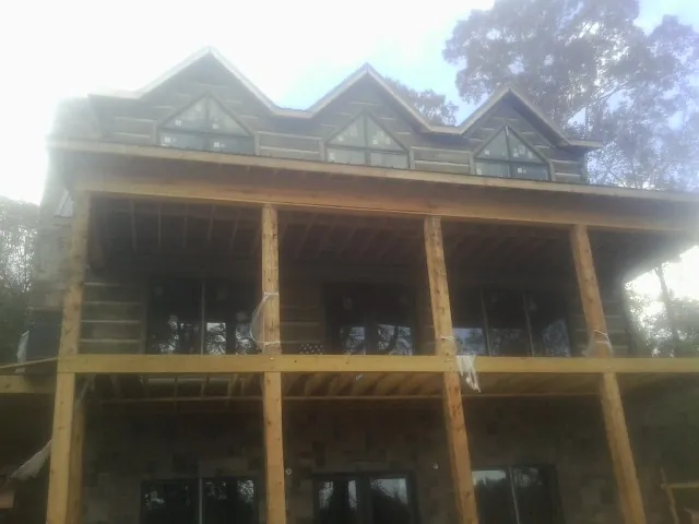Dormers and porch framing on a large log home under construction — Roof Coating work by our crew in Maywood