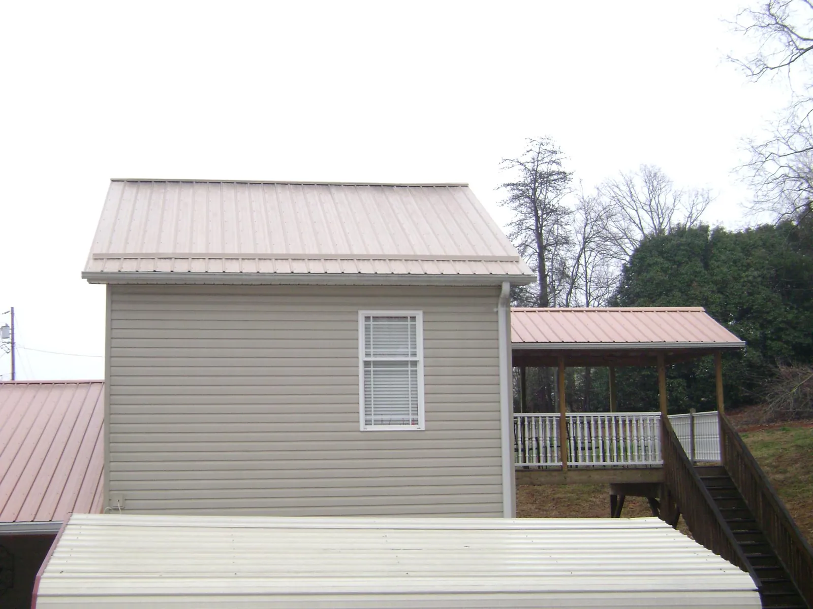 Tan metal roofs on a two story addition and attached porch, from a Roof Replacement job in Maywood